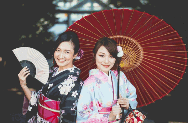 Foto de duas mulheres de kimono, usando sombrinha e leque. Muitas curiosidades sobre o Japão envolvem vestimentas e acessórios.