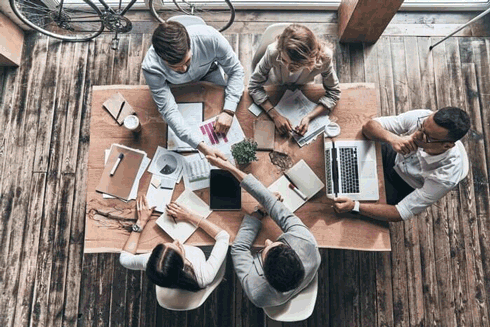 Foto de um grupo de pessoas trabalhando juntas em uma mesa. A coordenação é um dos exemplos de habilidades profissionais atualmente desejadas pelo mercado