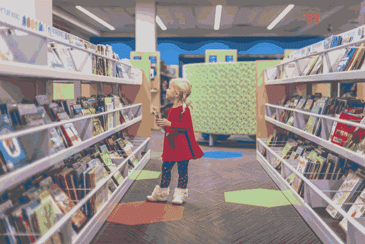 Foto de menina em livraria. A alfabetização é muito importante para descobrir o mundo.