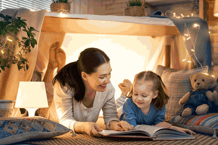 Foto de mãe e filha lendo juntas, deitadas no chão. Os pais podem ajudar muito na alfabetização com atitudes simples.