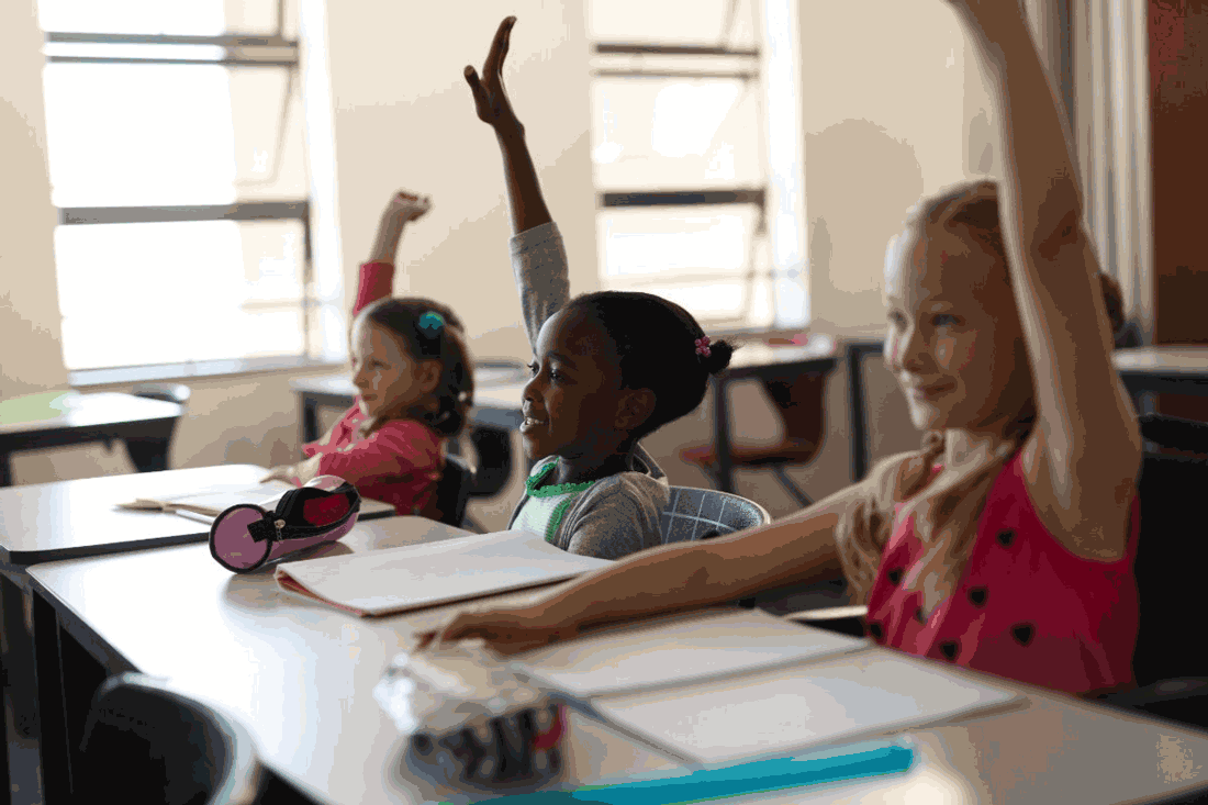 Foto de três crianças em sala de aula, com os braços levantados.  A idade escolar obrigatória para ingressar na escola é 4 anos, segundo a.