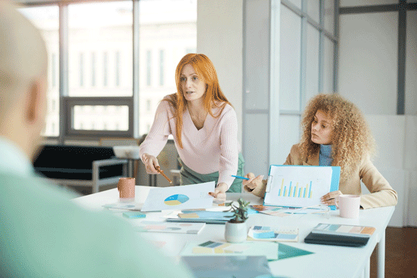 Foto de duas mulheres, uma ruiva e outra negra, em uma reunião de negócios. O empreendedorismo feminino apresenta muitos desafios.