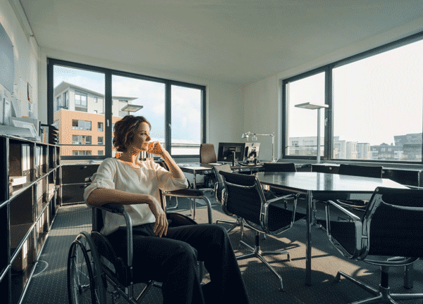 Foto de mulher em cadeira de rodas, pensativa em um escritório. O empreendedorismo feminino traz muitos benefícios para as empresas e a sociedade.