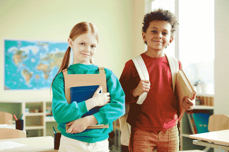 Foto de menino e menina sorridentes em sala de aula. A retenção de alunos é fundamental para o sucesso do negócio.