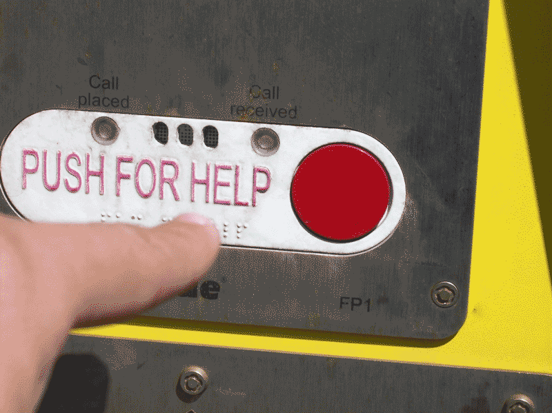 Foto de dedo apertando botão vermelho com letreiro push for help. Push é um dos falsos cognatos mais conhecidos, pois significa empurre.